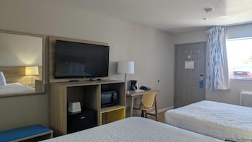 Habitación de hotel con dos camas, una televisión, un escritorio con lámpara y una ventana con cortinas.