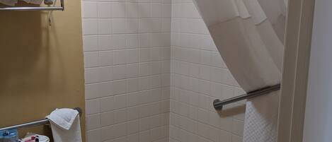A bathroom with a shower, toilet, and a shelf with towels.
