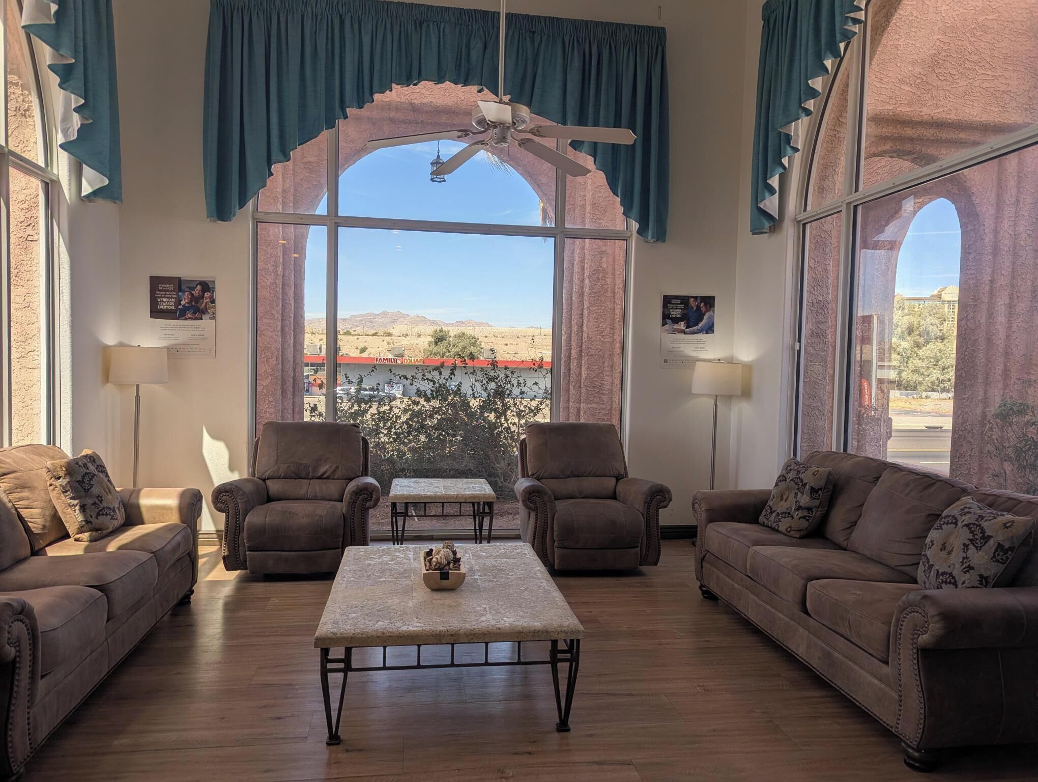 A spacious living room with a large arched window, two sofas, a coffee table, and a ceiling fan.