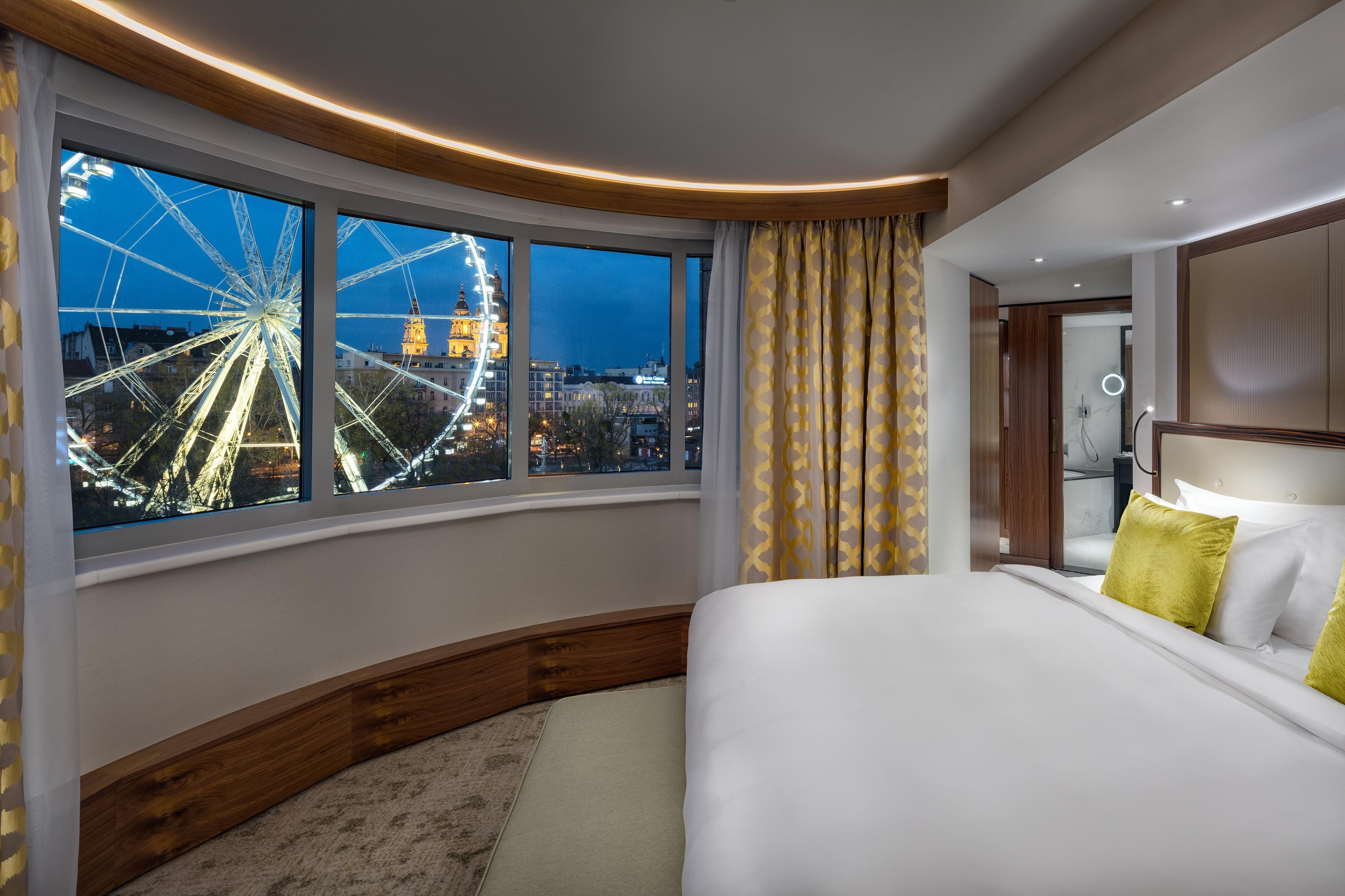 Habitación de hotel con una cama grande, vista a una noria y diseño moderno.