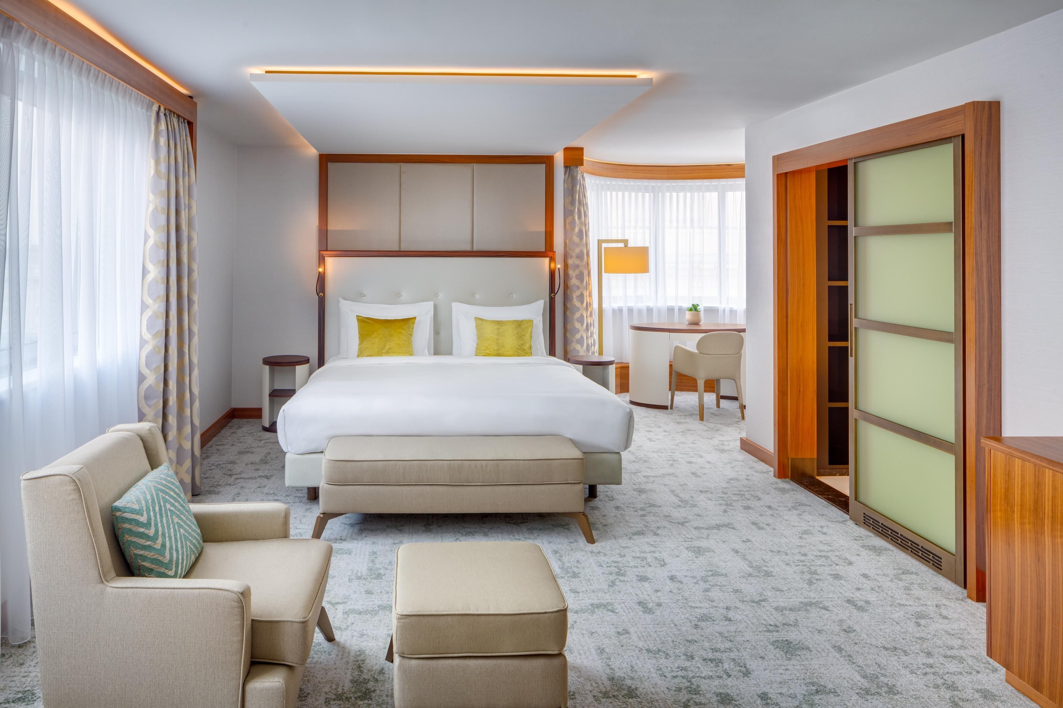 A hotel room with a large bed, a desk, a chair, and a sofa.