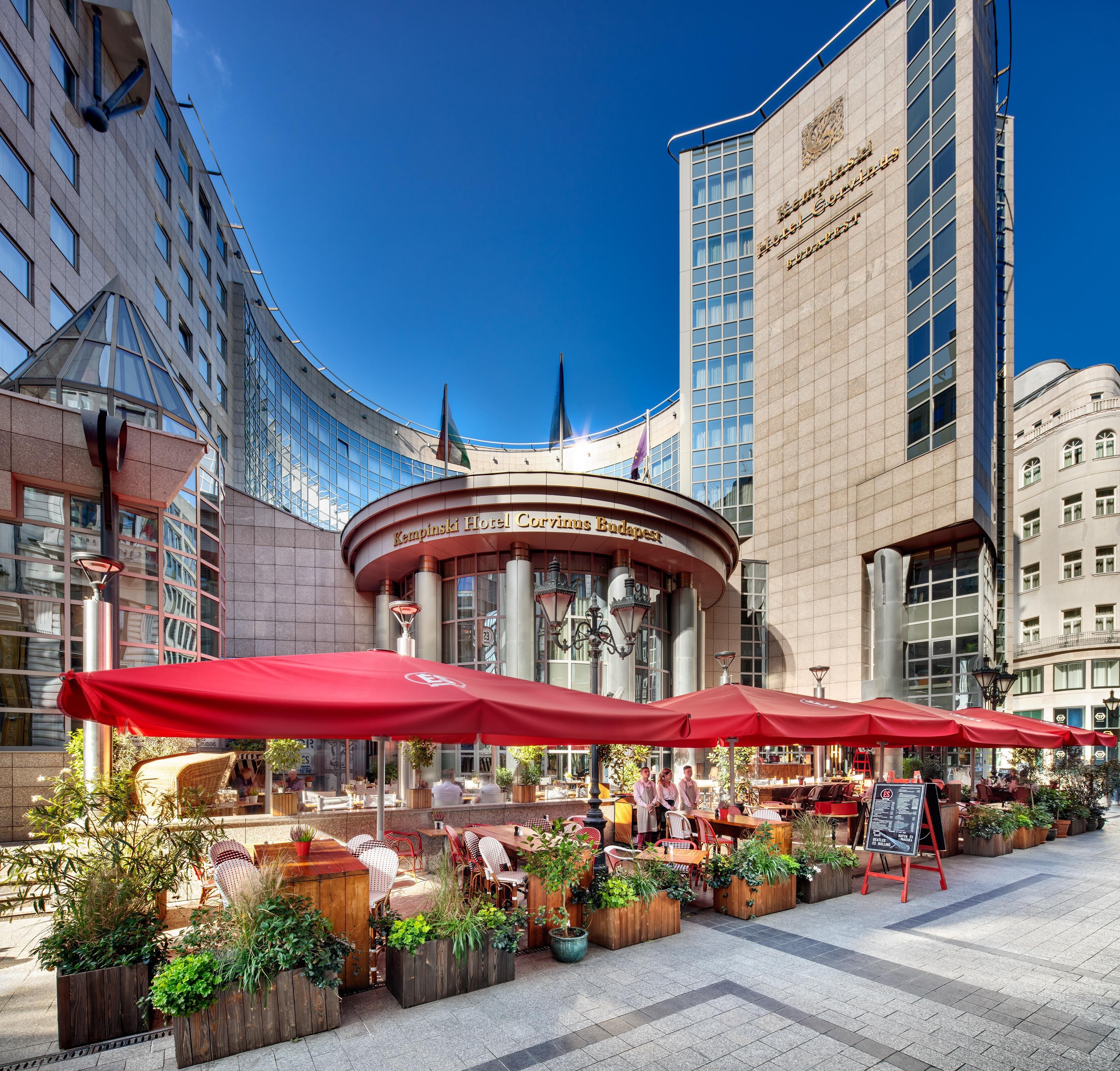 A hotel with outdoor seating and a clear view of the building's facade.