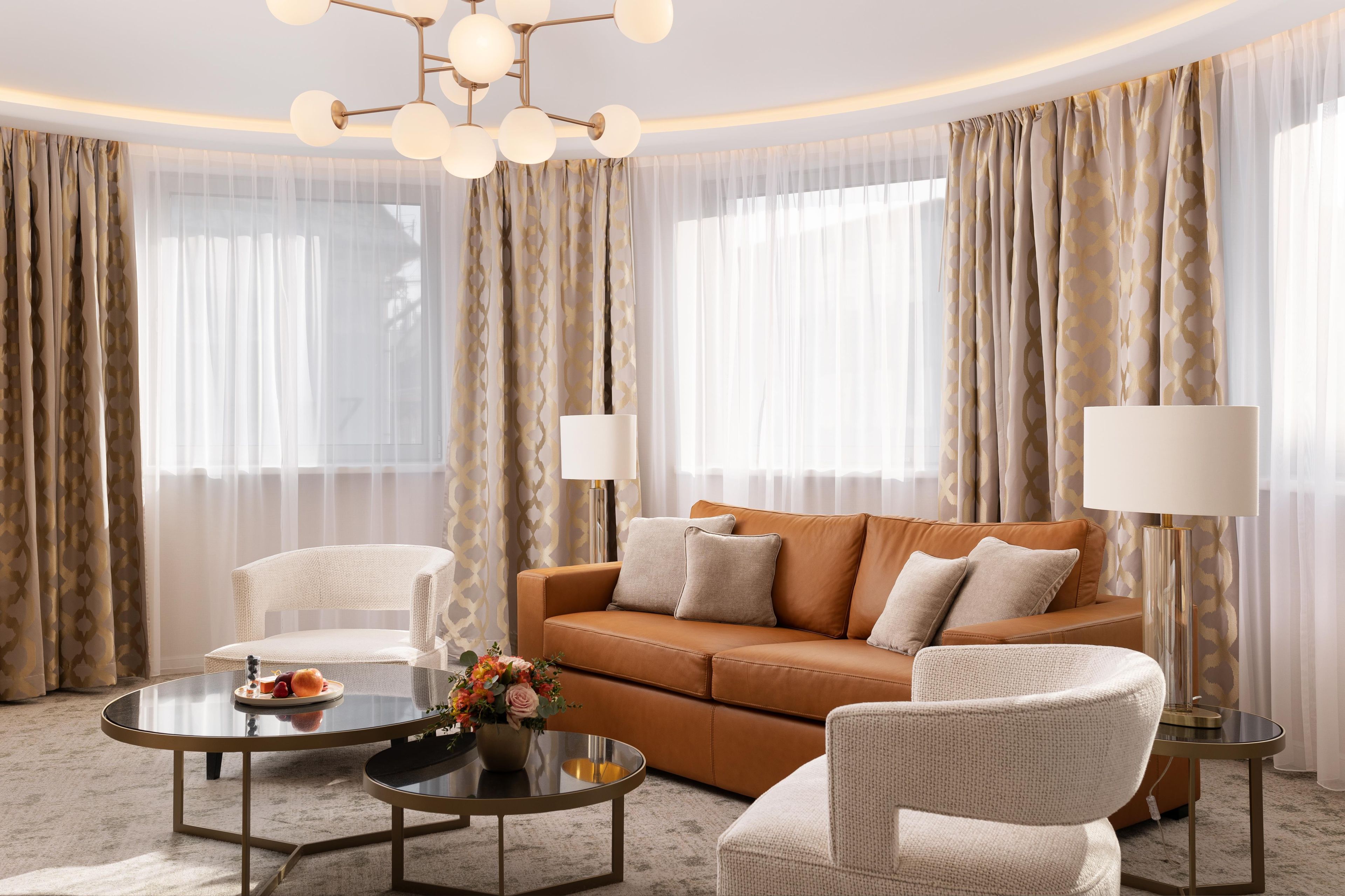 A modern living room with a leather sofa, two armchairs, a glass coffee table, and a floor lamp.
