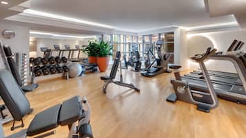 Un gimnasio moderno con cintas de correr, elípticas, pesas libres y una máquina de remo.