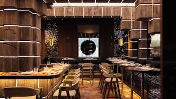 A restaurant interior with a central bar, seating arrangements, and a decorative wall.