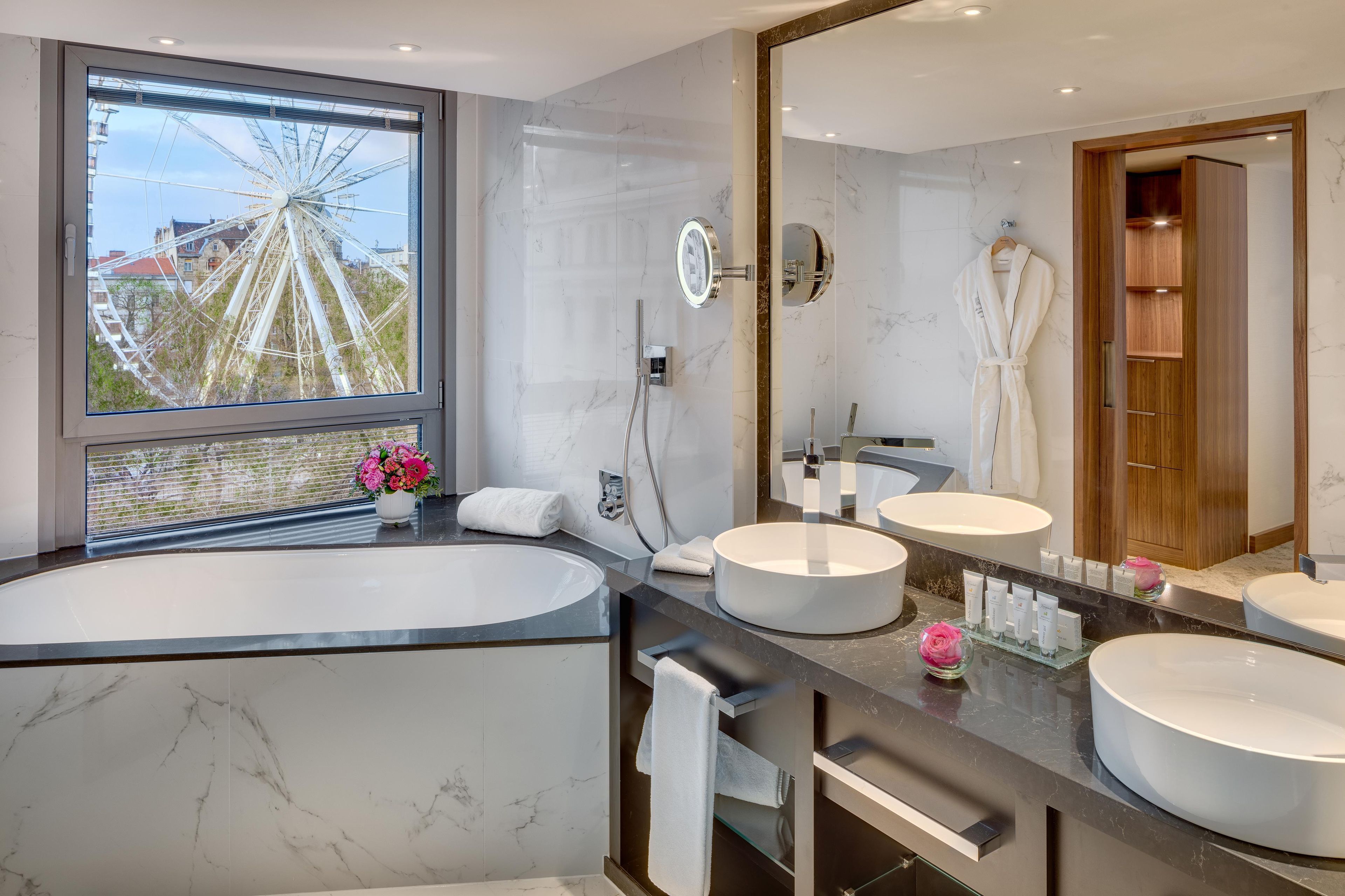 Une salle de bain moderne avec une grande baignoire, deux lavabos et un grand miroir.