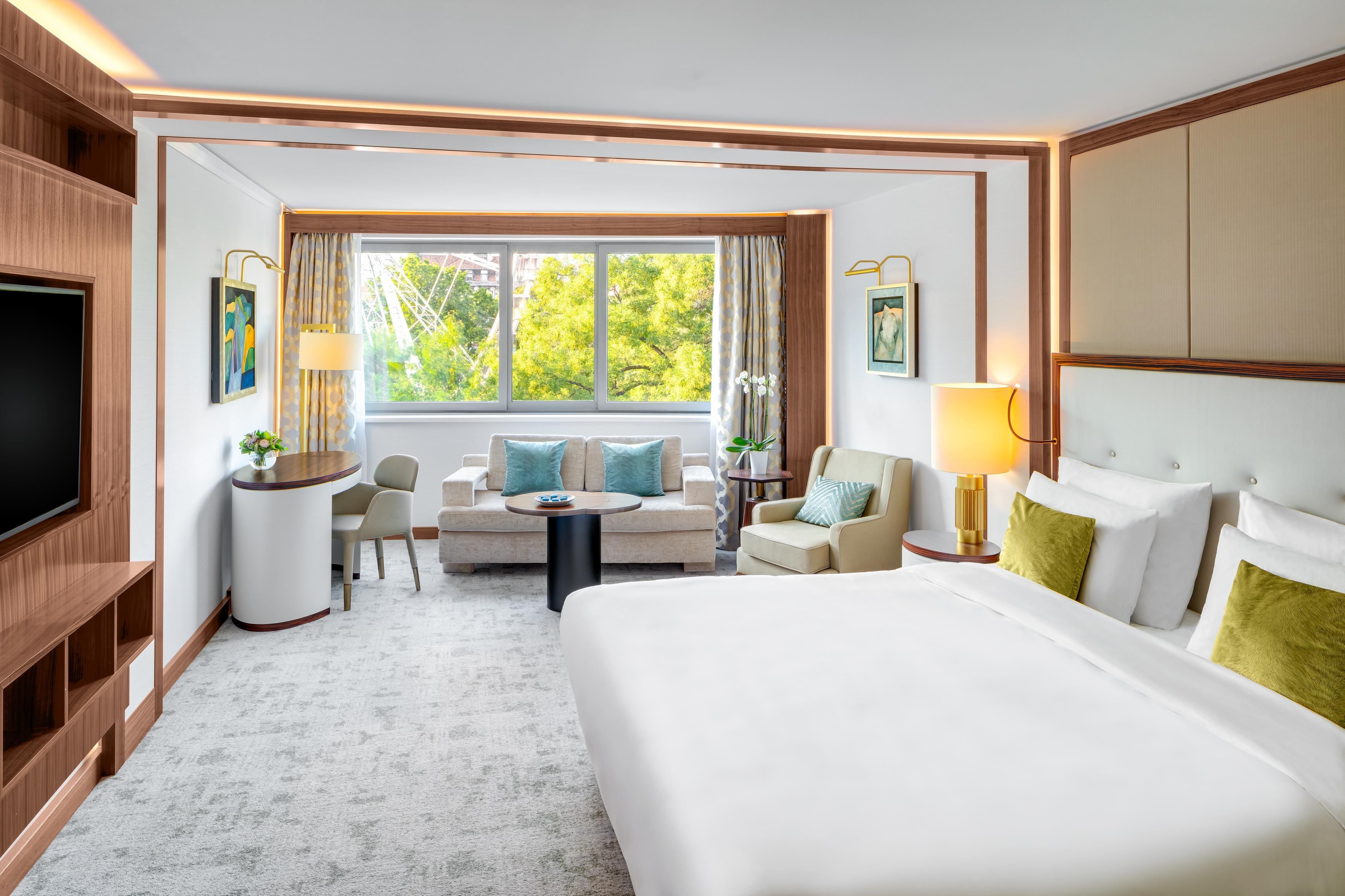 A hotel room with a large bed, a sofa, a small table, and a TV.