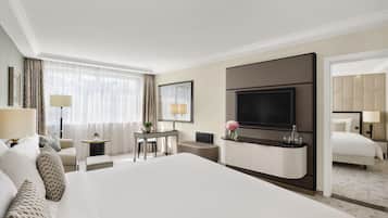 Habitación de hotel con una cama grande, un escritorio con silla, televisión y un baño visible a través de una puerta abierta.