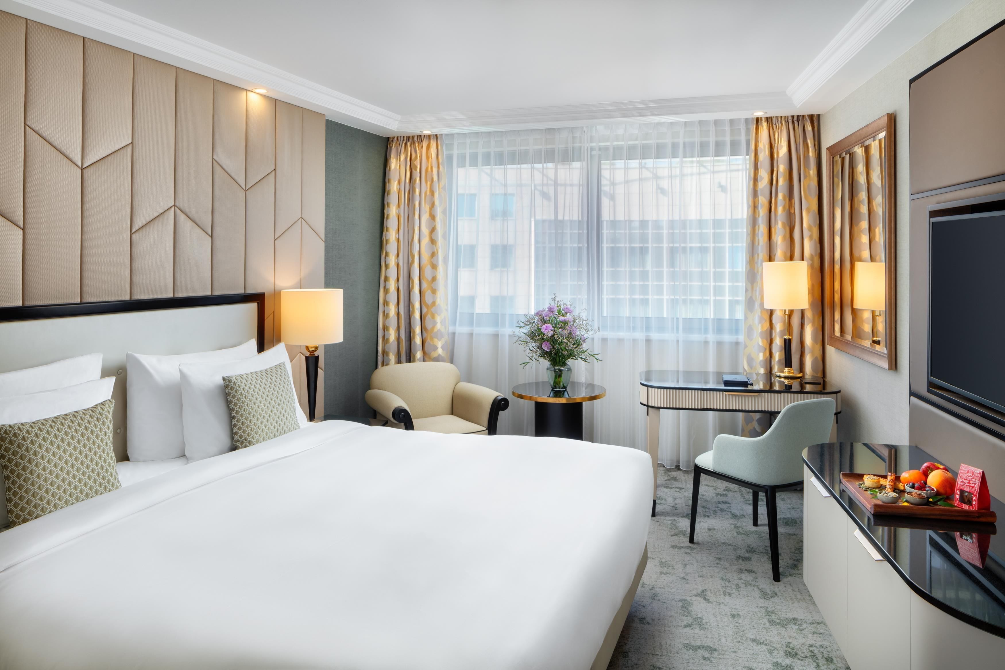 Una habitación de hotel con una cama grande, un escritorio, una silla y un televisor.