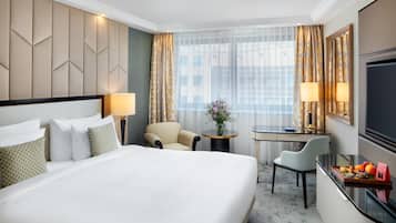 Una habitación de hotel con una cama grande, un escritorio, una silla y un televisor.