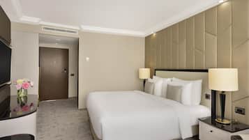 Una habitación de hotel con cama, mesitas de noche, televisión y una lámpara de pared.