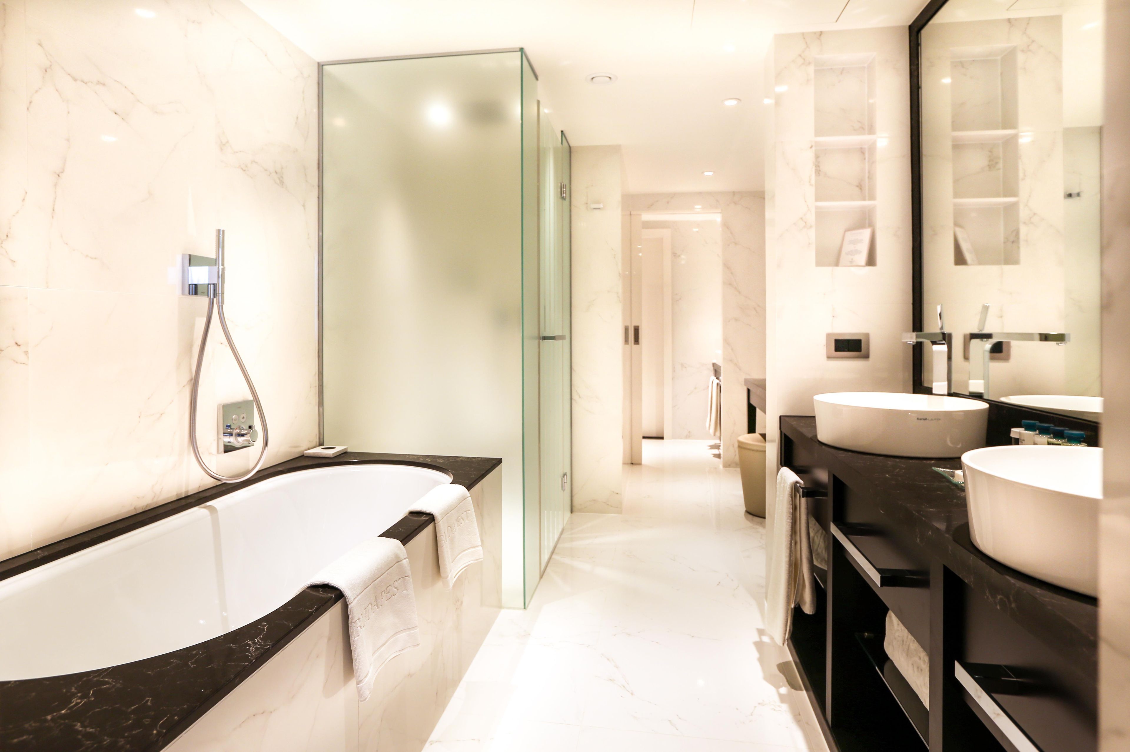 A modern bathroom with a glass-enclosed shower, a freestanding bathtub, and a vanity with a large mirror.