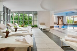 A spa area with lounge chairs, a pool, and large windows. - Kempinski Hotel Corvinus Budapest (Budapest)
