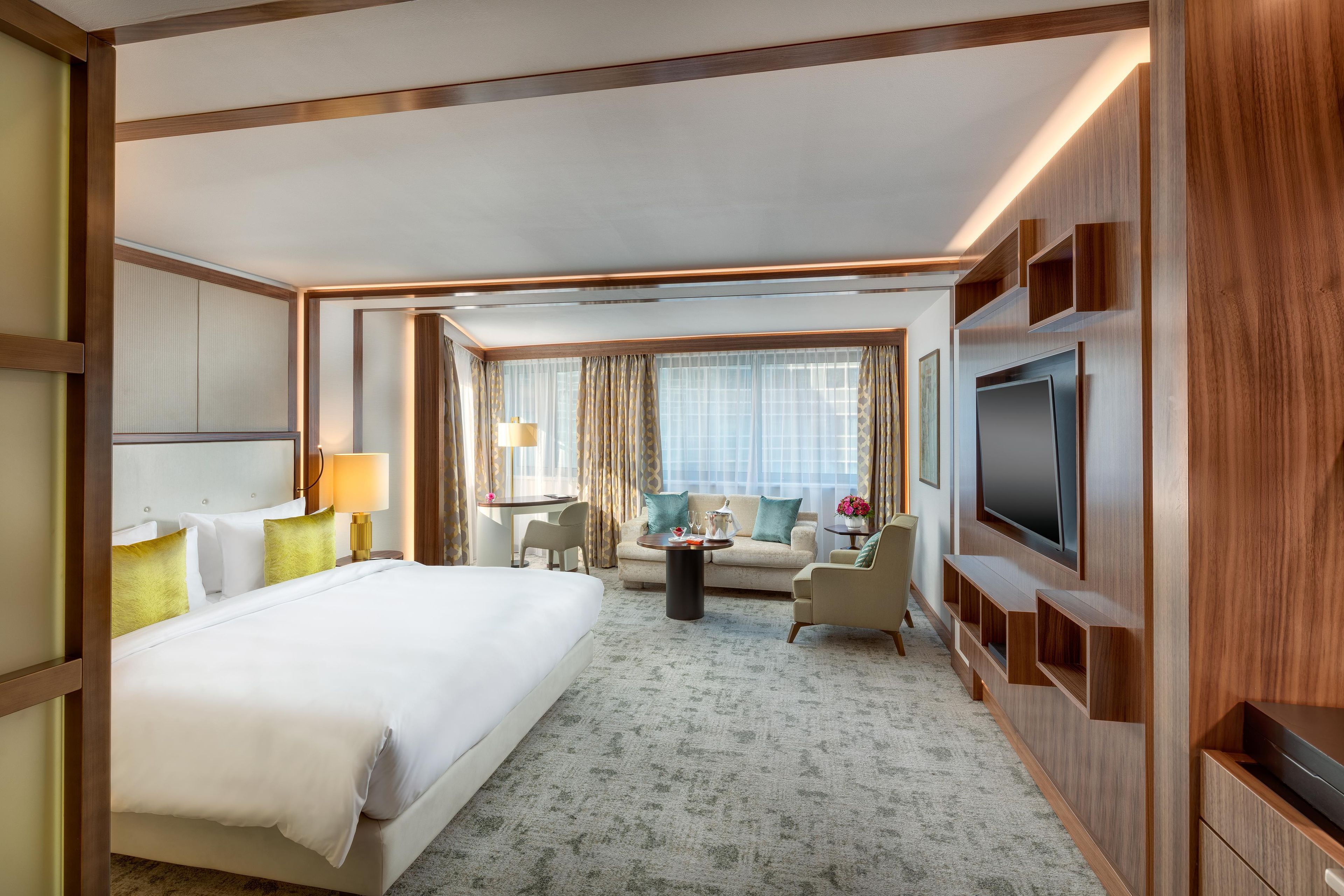A hotel room with a large bed, a sofa, a TV, and a desk.