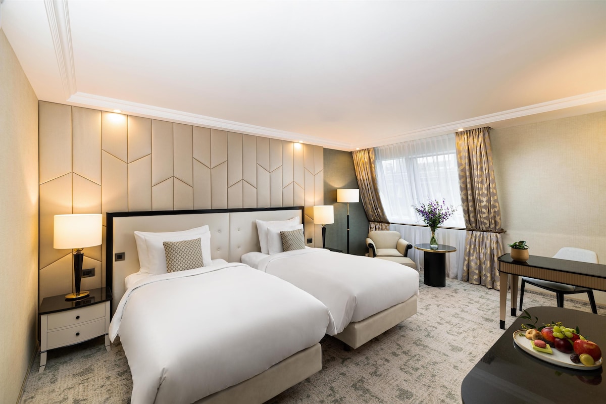 Een hotelkamer met twee bedden, een bureau, een stoel en een eettafel.