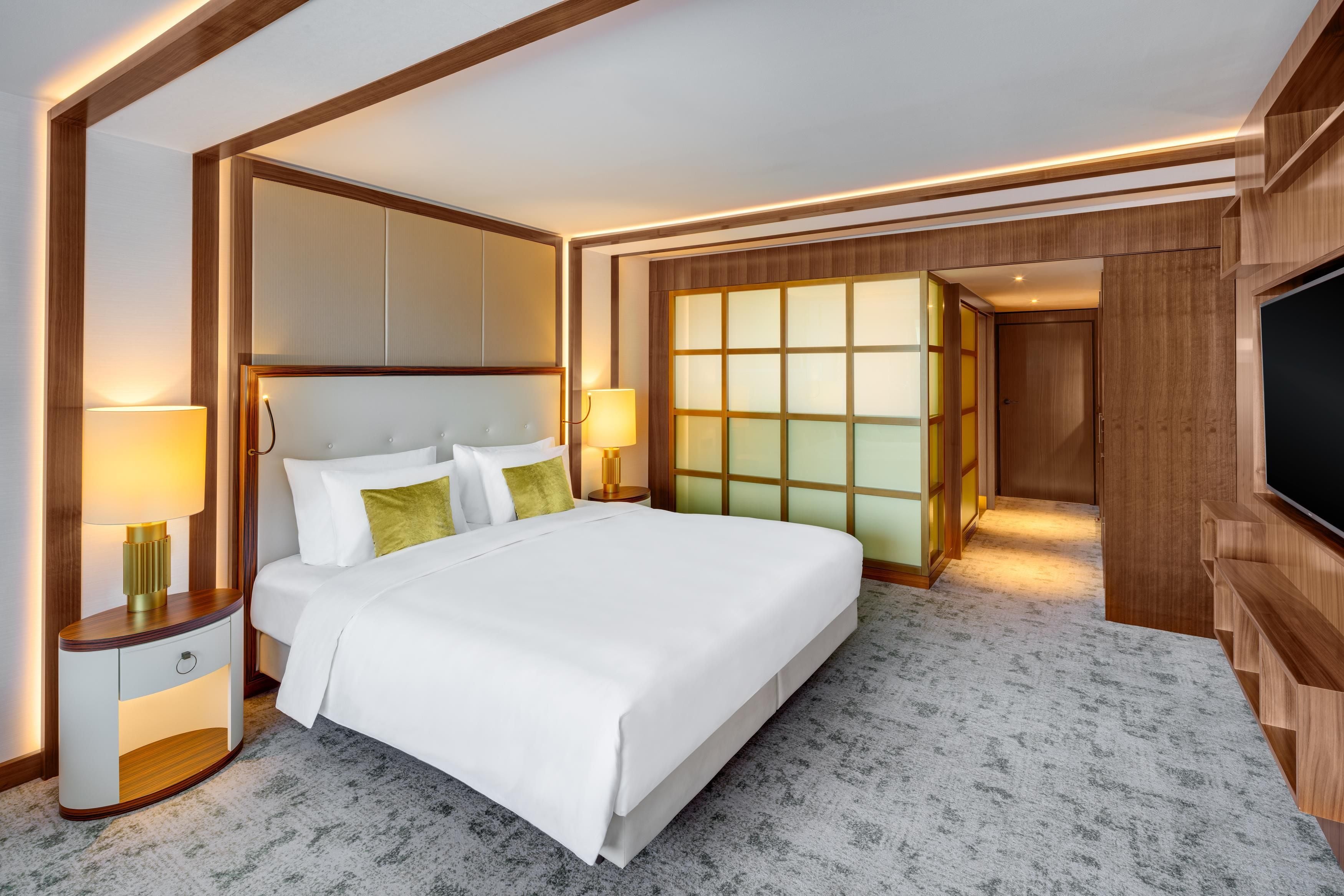 A hotel room with a large bed, bedside lamps, a wardrobe, and a television.