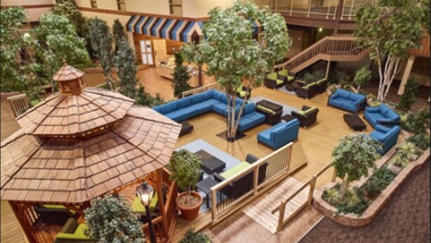 An indoor atrium with a central seating area, a small gazebo, and surrounding greenery.
