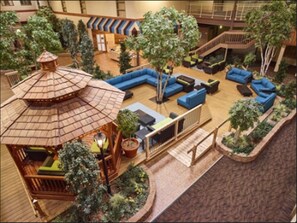 An indoor atrium with a central seating area, a small gazebo, and surrounding greenery. - LivINN Hotel Minneapolis North / Fridley (Fridley)