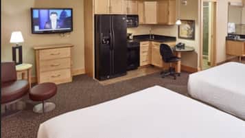 A hotel room with a bed, a desk, a chair, a television, a refrigerator, and a microwave.