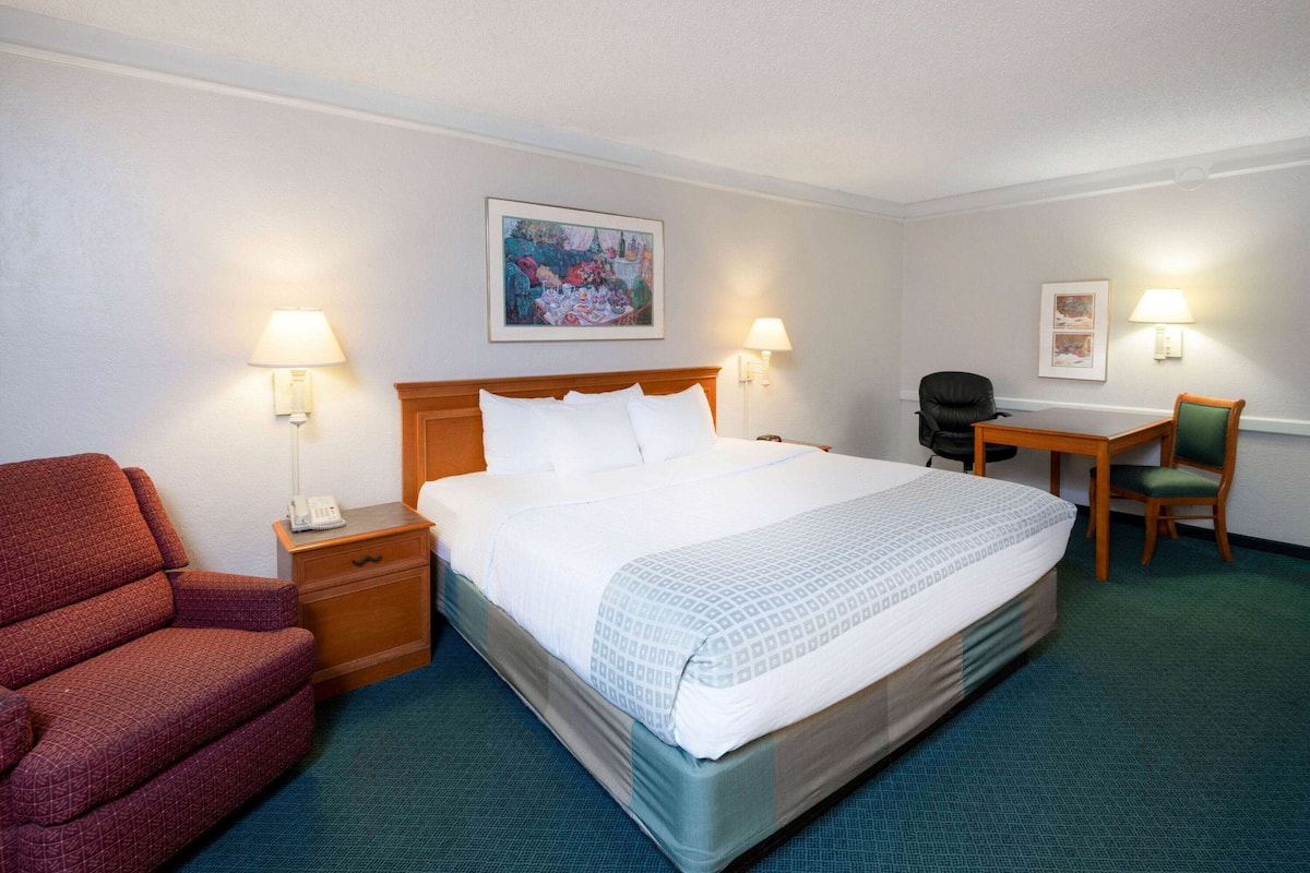 Una habitación de hotel con cama, escritorio, silla y teléfono sobre una mesita de noche.