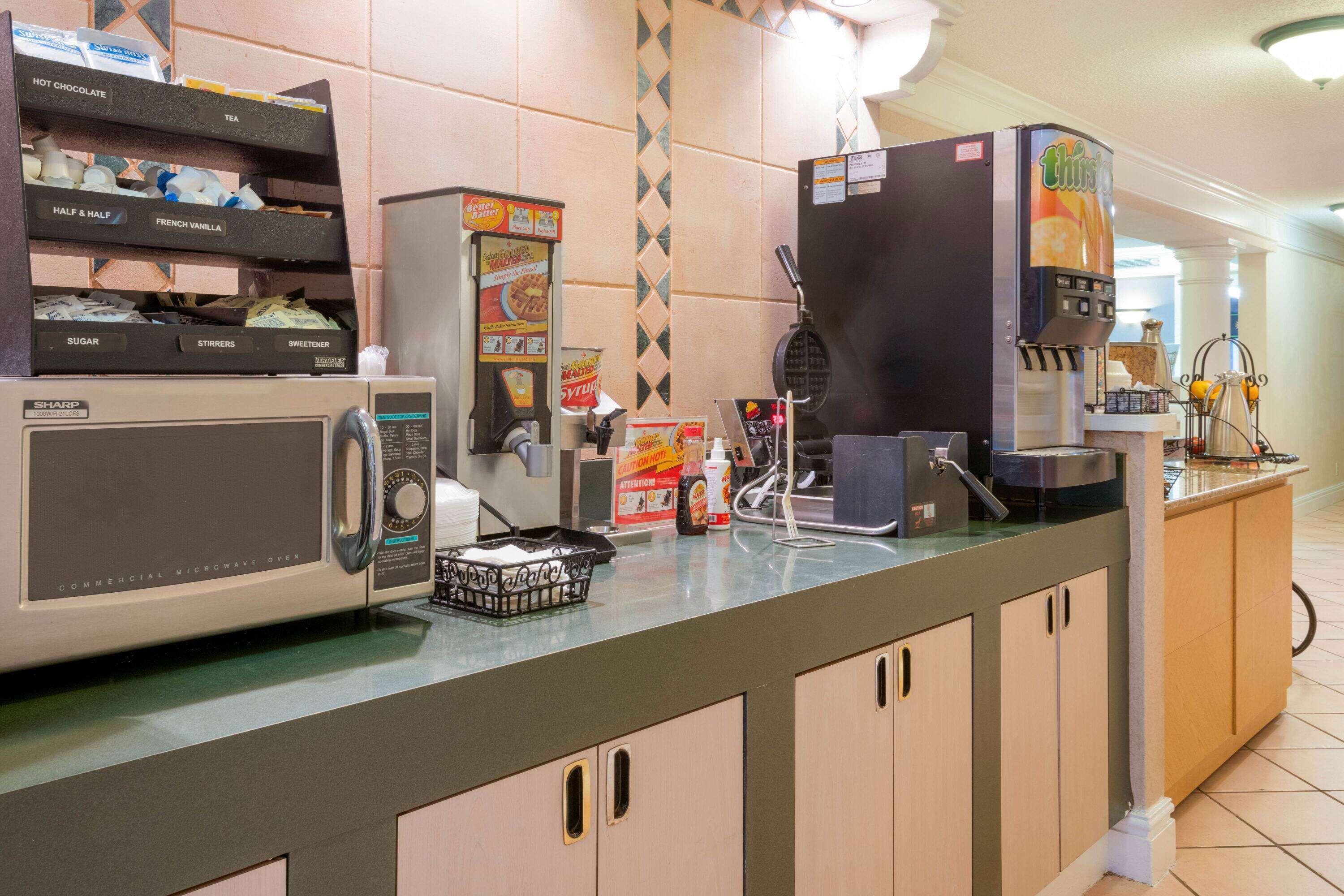 Une cuisine professionnelle équipée d’un four à micro-ondes, d’une machine à café et d’un appareil à gaufres.