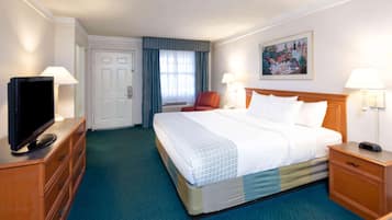 Een hotelkamer met een groot bed, een televisie op een dressoir, een bureau met een lamp en een schilderij aan de muur.