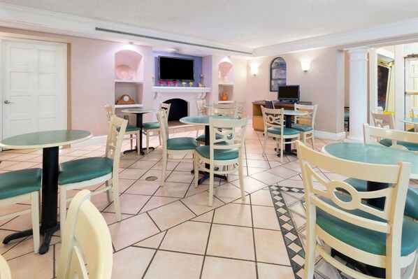 Un comedor con mesas y sillas redondas, una chimenea y un televisor.