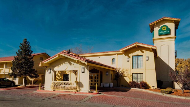 A hotel with a prominent tower, a covered entrance, and a clear blue sky. - La Quinta Inn by Wyndham Farmington (Farmington)