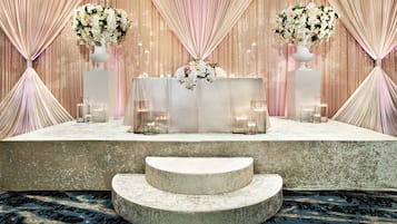 A stage with a white table, two vases with flowers, and candles.