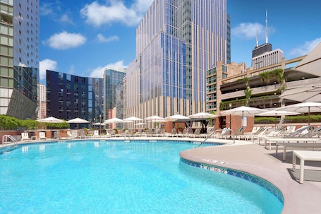 Una piscina al aire libre, camas de piscina con cargo, sombrillas