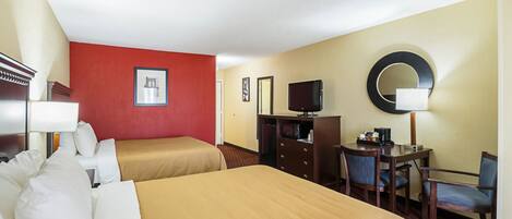 Une chambre d’hôtel avec deux lits, un bureau, une télévision, un miroir et un mur d’accent de couleur rouge.