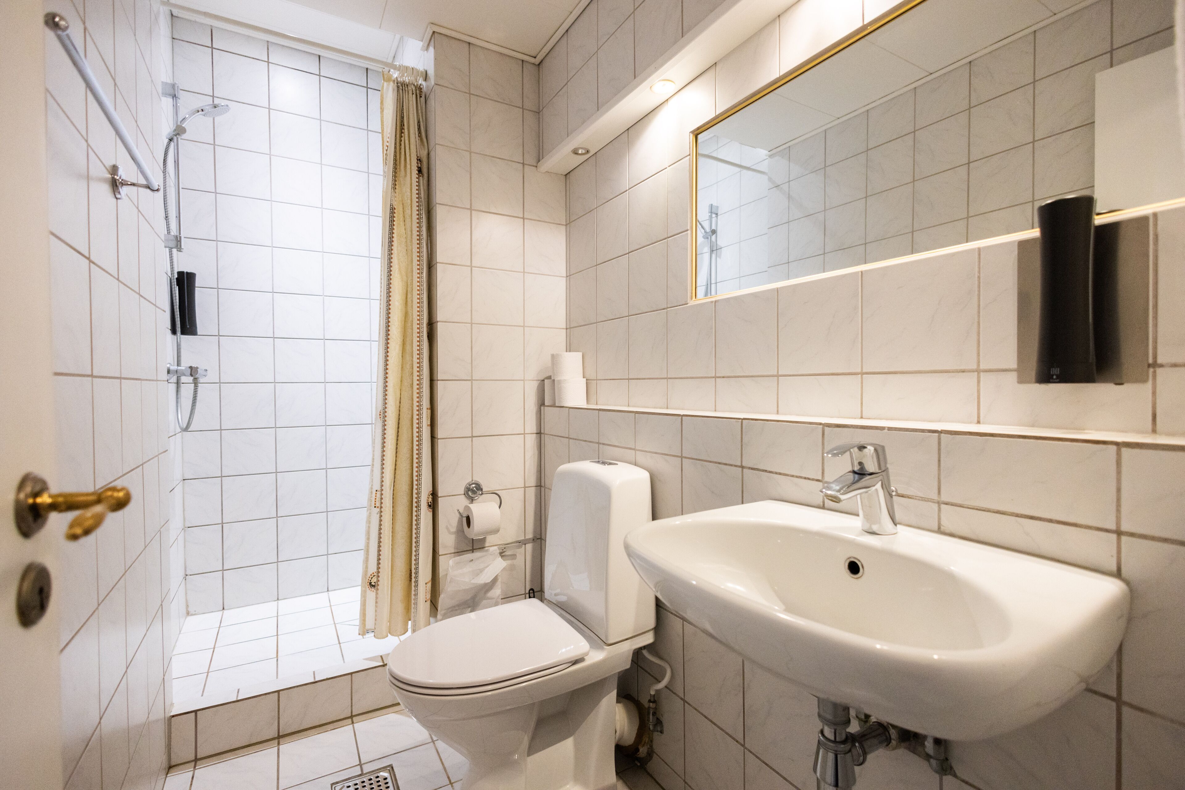 A modern bathroom with a toilet, sink, shower, and mirror.