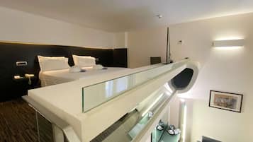 Een moderne hotelkamer met een groot bed, een balkon met glazen wanden, een bureau en een stoel.