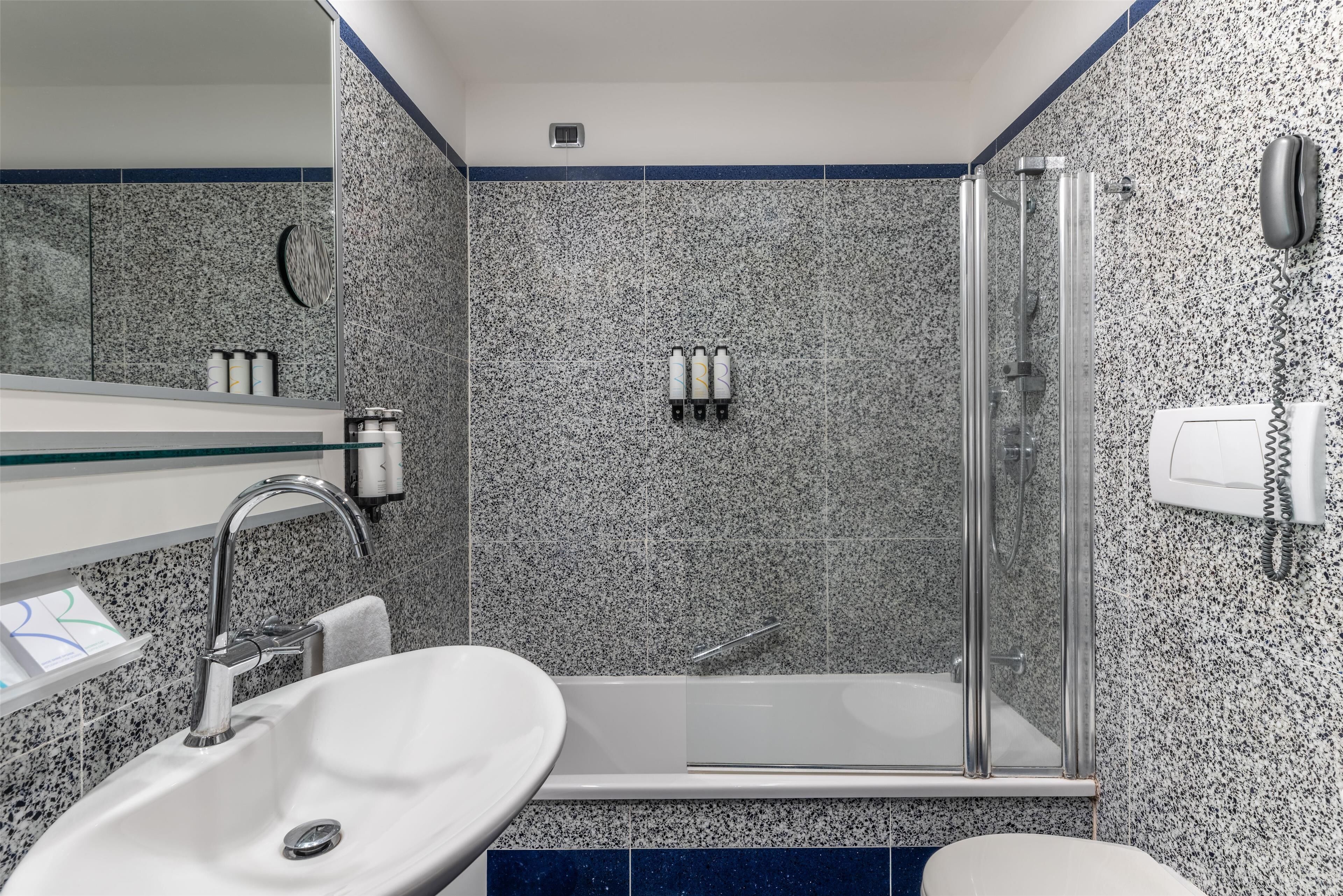 A bathroom with a sink, mirror, shower, and toilet.
