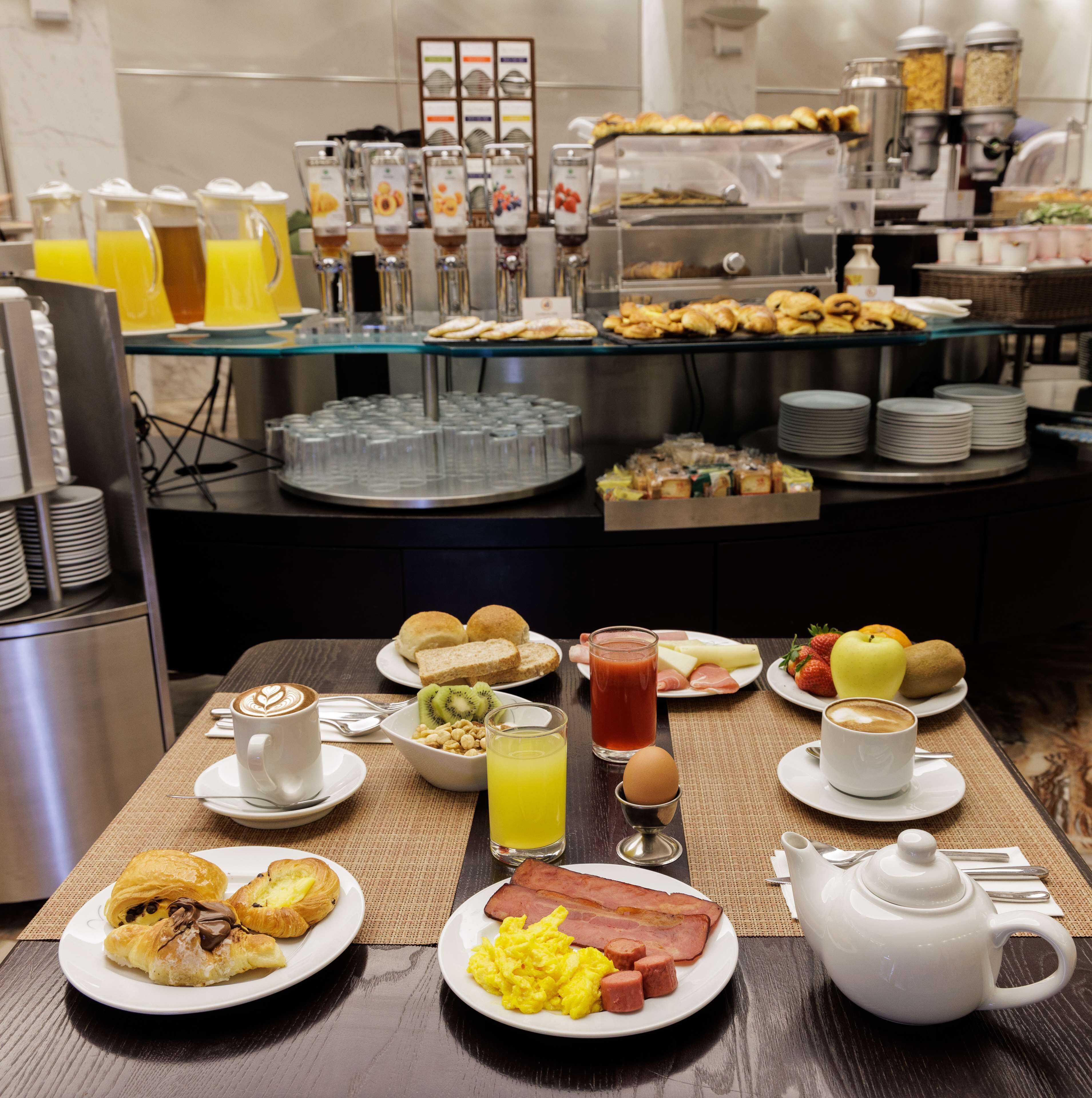 Un bufé de desayuno con diversas opciones de comida, bebidas y una tetera sobre una mesa.