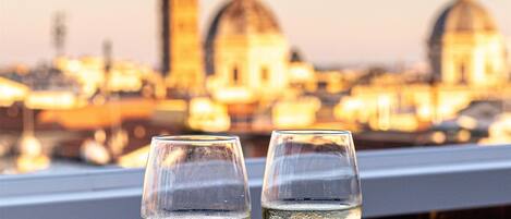 A table with three glasses of water and a menu, set against a cityscape view at sunset.