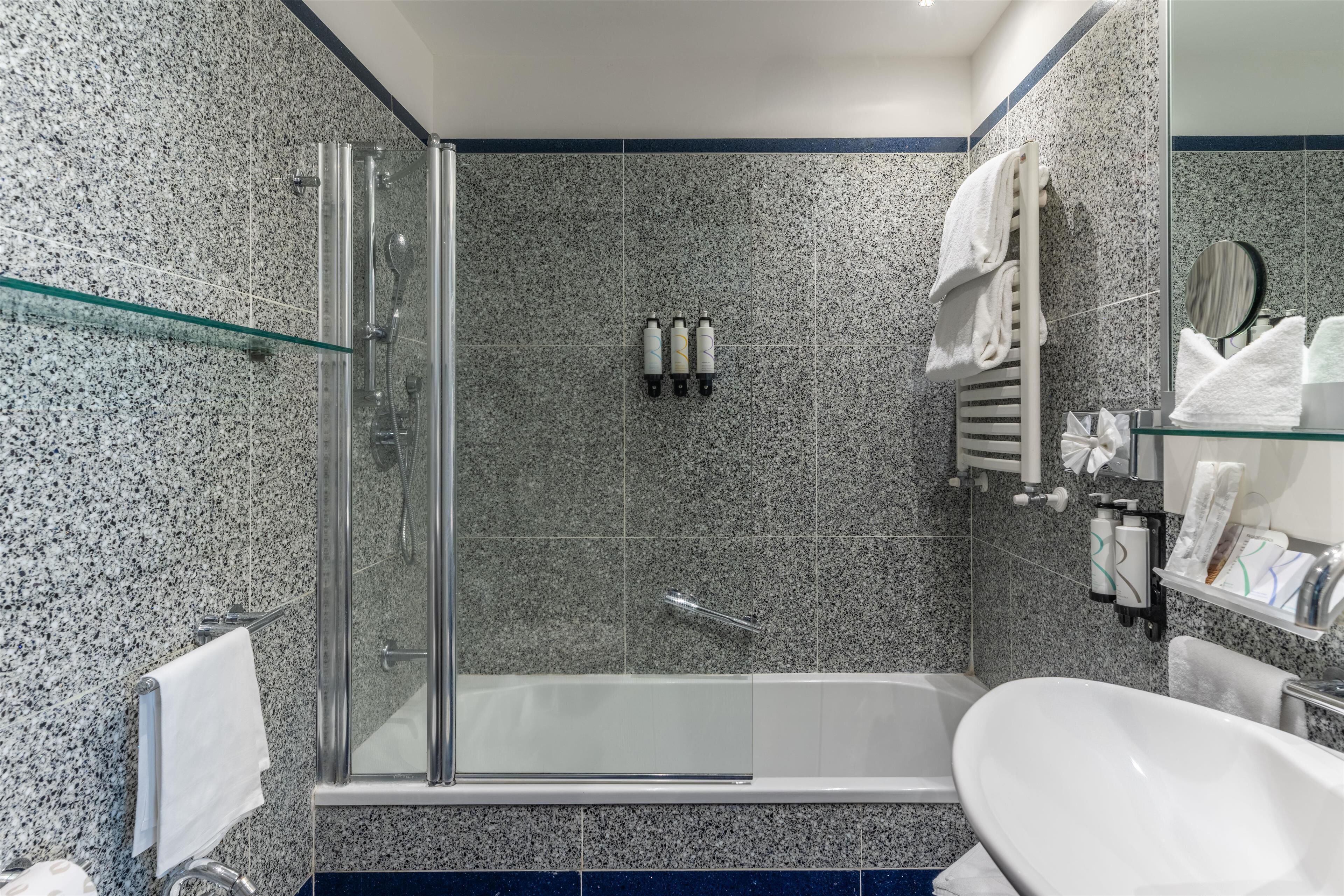 A modern bathroom with a glass-enclosed shower, a freestanding bathtub, and a white sink.