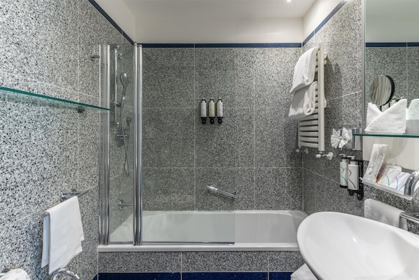 Un baño moderno con ducha de vidrio, una bañera independiente y un lavamanos blanco.