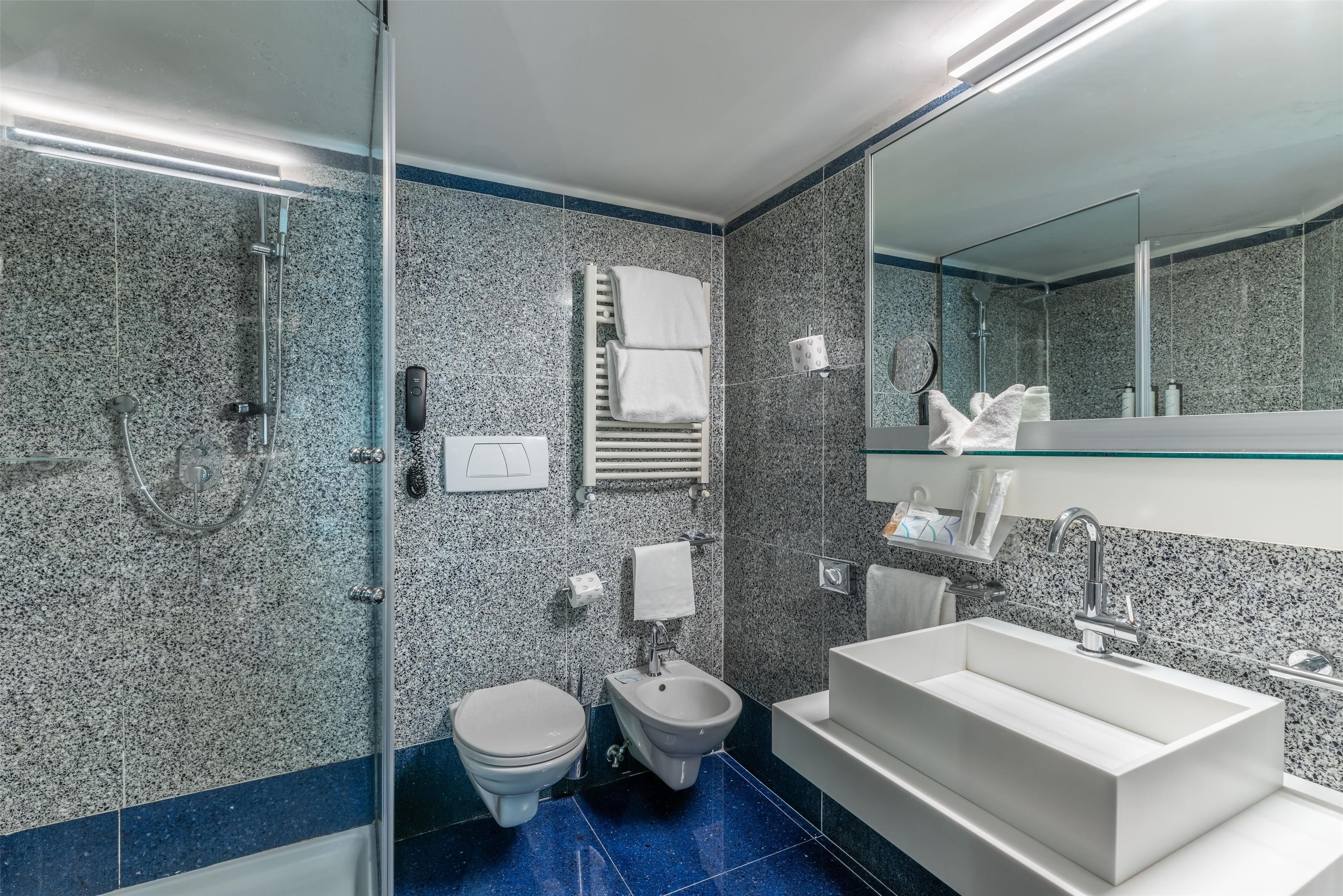 A modern bathroom with a bidet, toilet, and a large sink.
