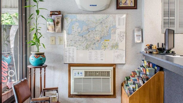 Uma área de recepção com mapa, ar condicionado e uma estante de livros.