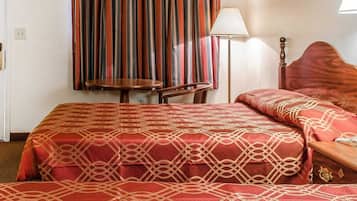 Quarto de hotel com cama grande, mesa de cabeceira, abajur e janela com cortinas.