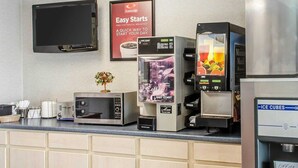 Uma cozinha compacta em hotel, com cafeteira, micro-ondas, torradeira e geladeira.