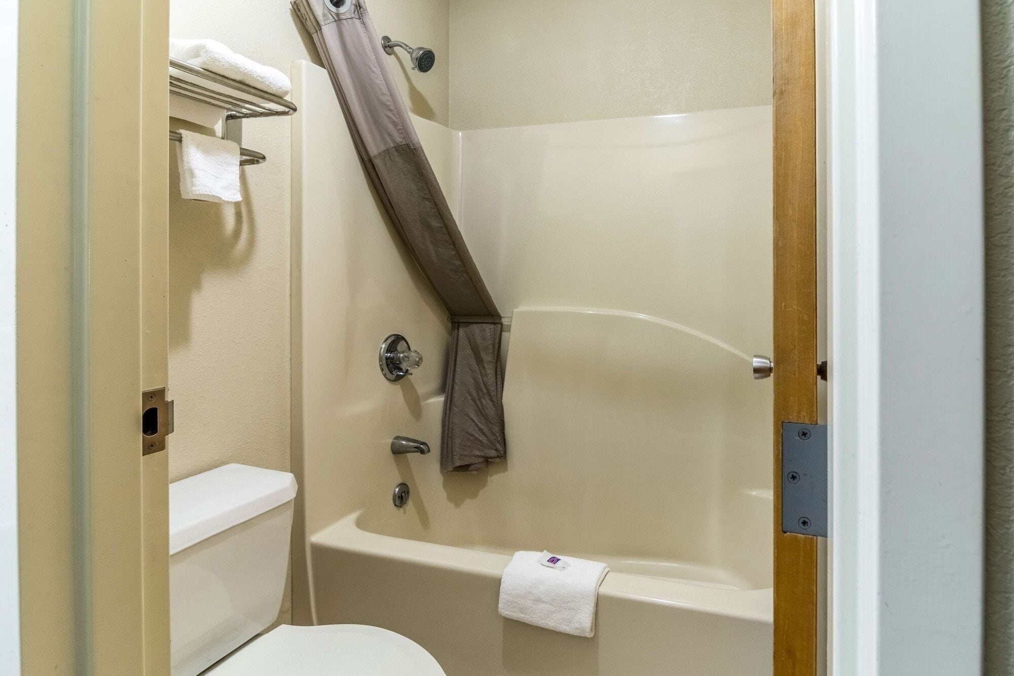 Et badeværelse med badekar, toilet og bruserforhæng.