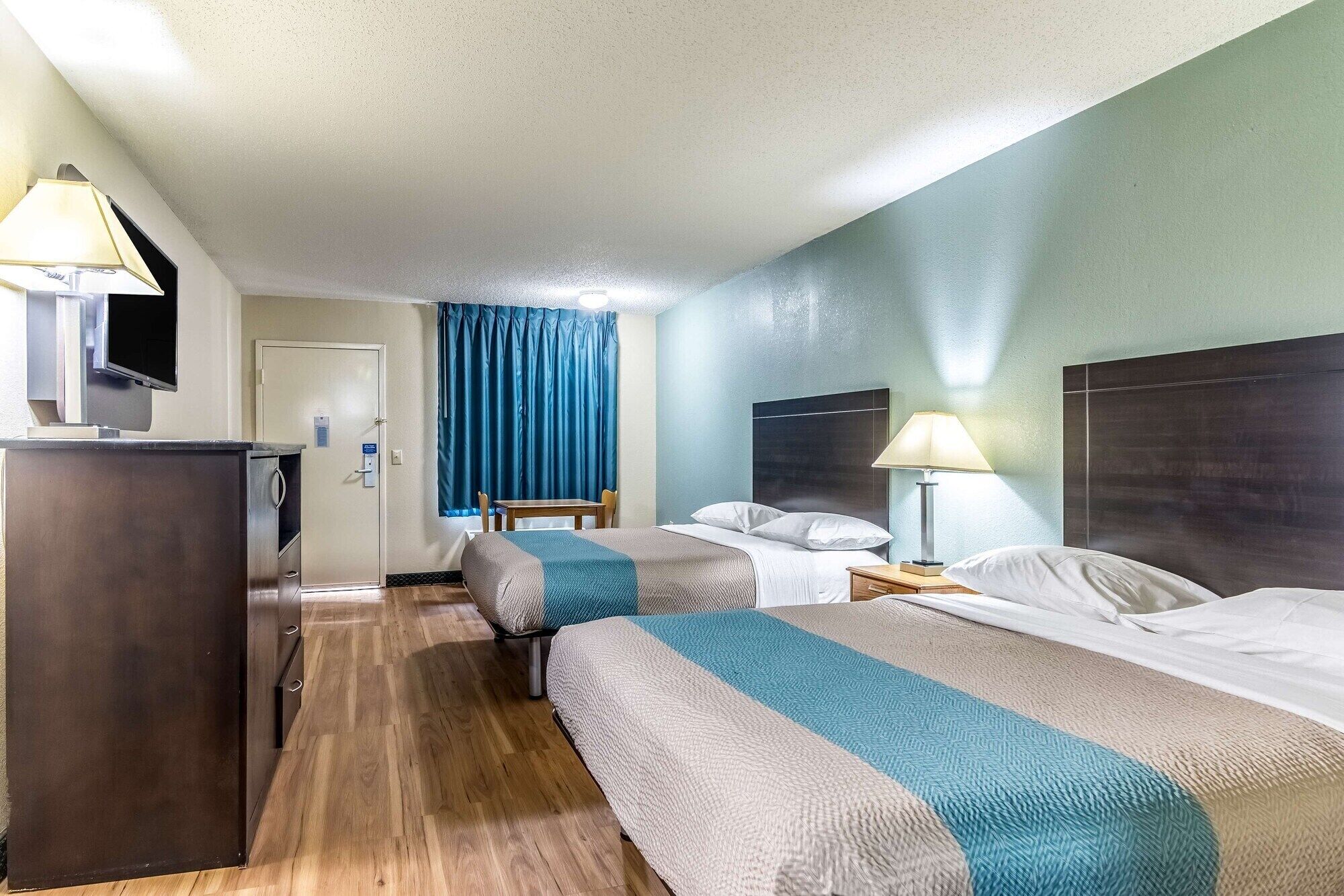 Une chambre d’hôtel avec deux lits, un bureau, une télévision et une salle de bain.