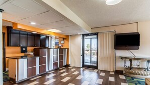 A hotel lobby with a reception desk, a flat-screen TV, and a patterned floor. - Motel 6 Kenly, NC (Kenly)