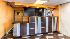 A hotel reception area with a counter, a door labeled "Manager," and a fire alarm on the wall. - Motel 6 Kenly, NC (Kenly)