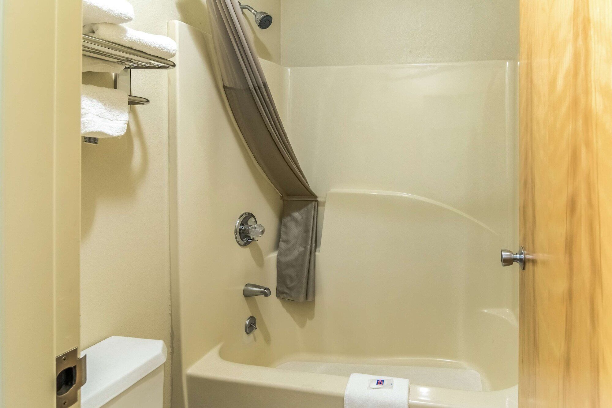 A small, enclosed shower area with a bathtub, a towel rack, and a shower curtain.
