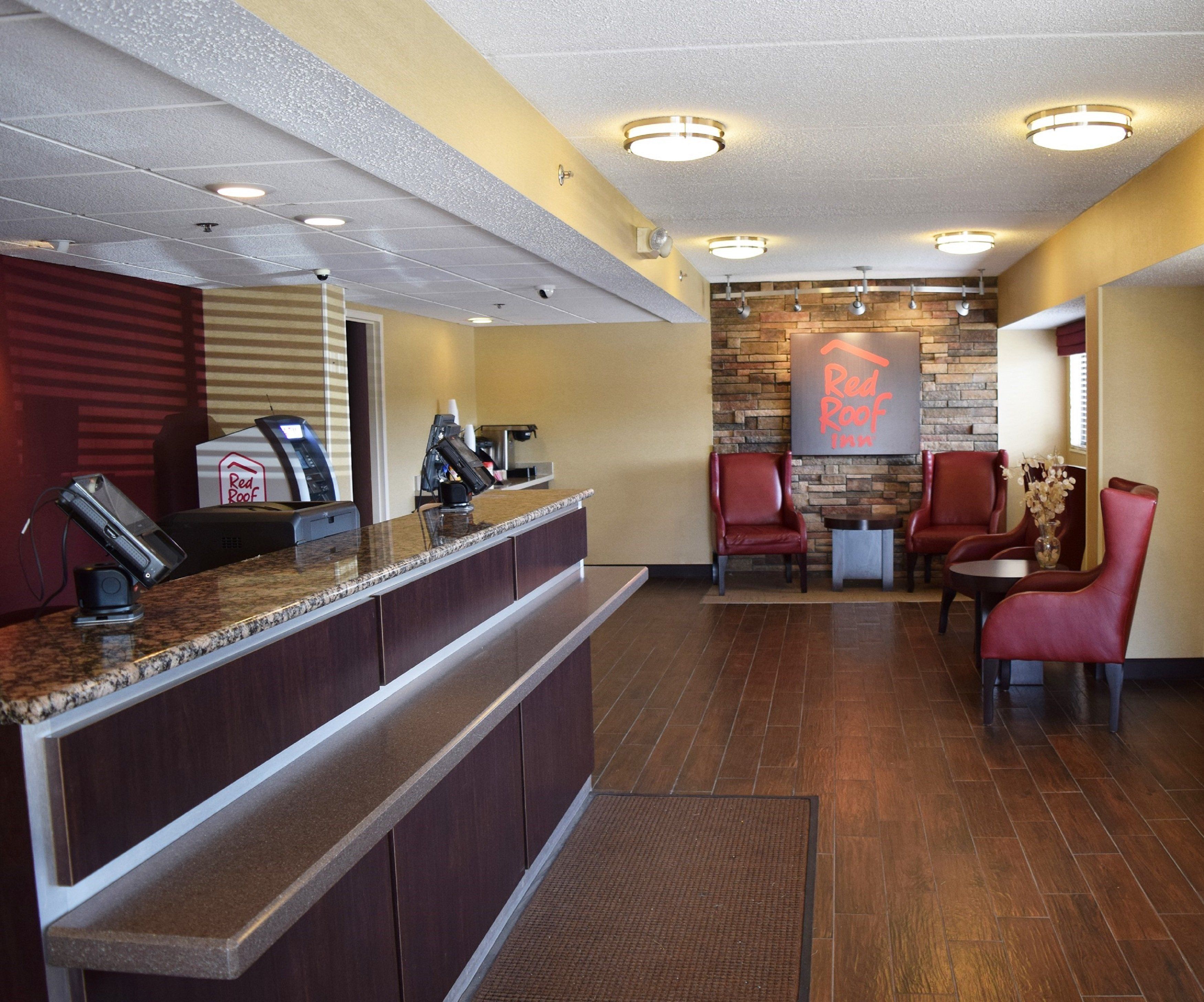 A hotel reception area with a counter, seating, and a wall-mounted sign.