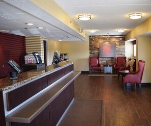 A hotel reception area with a counter, seating, and a wall-mounted sign.