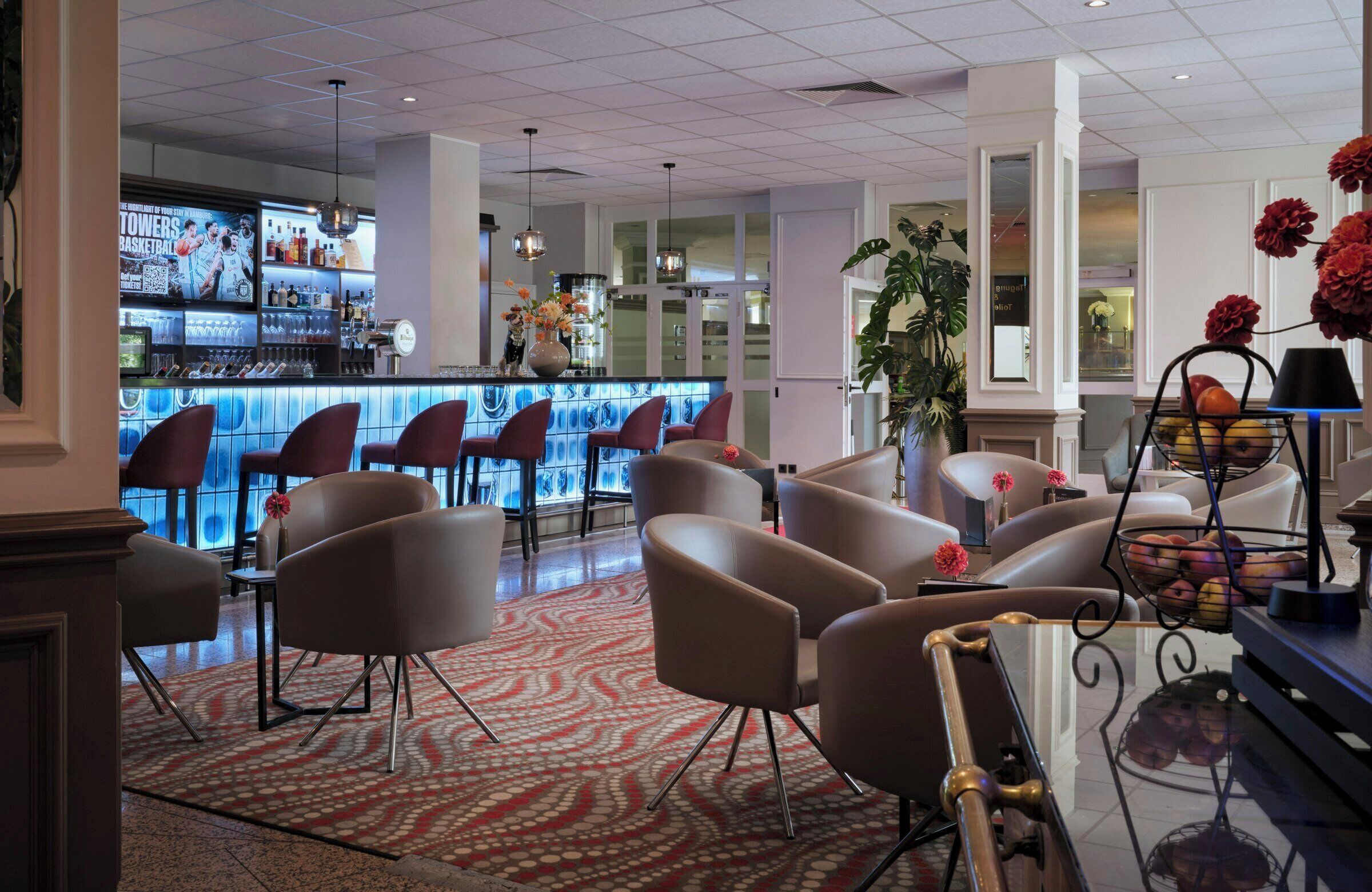 Eine Hotelhalle mit Barbereich, Sitzgelegenheiten und Dekorationselementen.